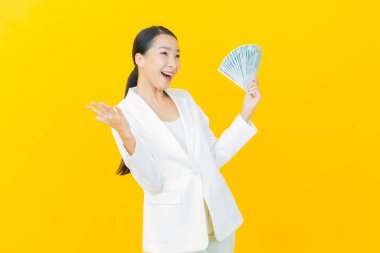 Asyalı güzel bir kadının portresi. Renkli arka planda bol para ve parayla gülümsüyor.