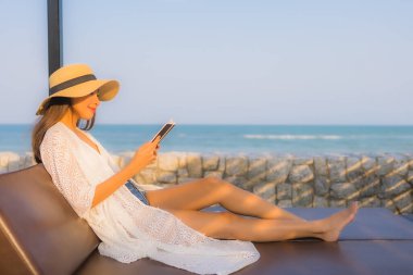 Portre genç Asyalı kadın seyahat tatilinde deniz kenarında kitap okudu.
