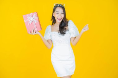 Güzel bir Asyalı kadının portresi. Arka planda kırmızı hediye kutusuyla gülümsüyor.