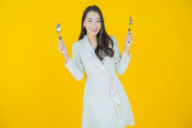 Güzel Asyalı bir kadının portresi kaşıkla ve çatalla gülümsüyor.