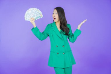 Asyalı güzel bir kadının portresi. Renkli arka planda bol para ve parayla gülümsüyor.