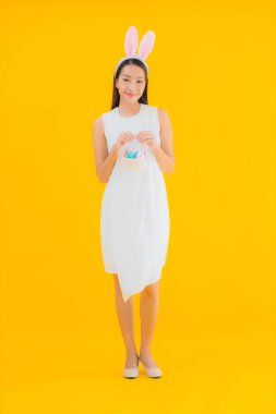 Sarı izole edilmiş arka planda paskalya yumurtası olan güzel Asyalı kadın portresi.