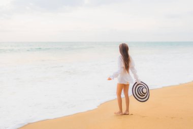 Güzel bir Asyalı kadın portresi deniz kenarında tatil yaparken rahatlar.