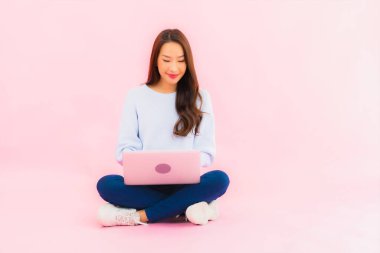 Portrait beautiful young asian woman use computer laptop on pink color isolated background