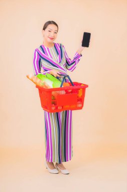 Marketten aldığı alışveriş sepetiyle güzel bir Asyalı kadının portresi. Renkli, izole arka plan.
