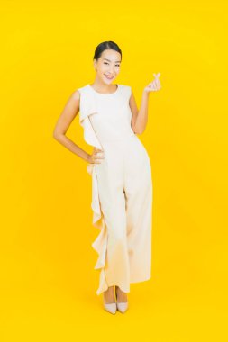 Asyalı güzel bir kadının portresi. Sarı arka planda hareketli gülümsüyor.