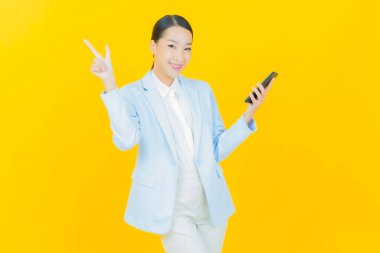 Renkli arka planda akıllı cep telefonuyla güzel Asyalı kadın gülümsemesi