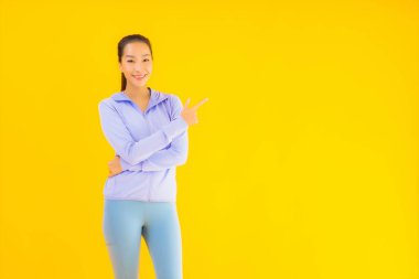 Sarı izole edilmiş arka planda spor giysili güzel Asyalı kadın portresi egzersize hazır.