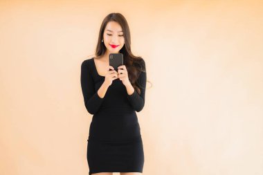 Güzel Asyalı genç bir kadının portresi mutlu bir şekilde gülümsüyor renkli arka planda akıllı cep telefonu kullan