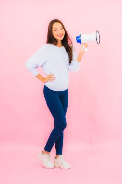 Portrait beautiful young asian woman with megaphone for communicate on pink isolated background