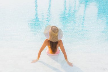 Güzel bir Asyalı kadın portresi. Tatil gezisinde deniz manzaralı açık havuz etrafında rahatça yüzebiliyor.