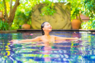 Güzel bir Asyalı kadın portresi. Rahatlayın, gülümseyin. Tatil için oteldeki yüzme havuzunun keyfini çıkarın.