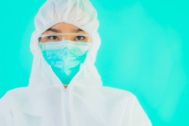 Güzel, genç Asyalı doktor kadın koronavirüsten korunmak için ppe ya da kişisel koruyucu ekipman takıyor ya da mavi izole arka planda beyaz kartı olan 19. bölgede yaşıyor.
