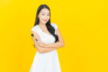 Sarı arka planda makyaj fırçası kozmetik olan güzel Asyalı kadın portresi