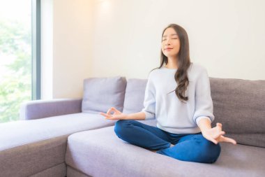 Oturma odasındaki kanepede güzel bir Asyalı kadın meditasyonu.