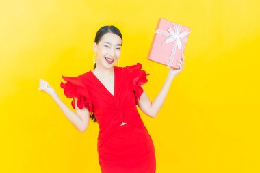 Güzel bir Asyalı kadının portresi. Arka planda kırmızı hediye kutusuyla gülümsüyor.