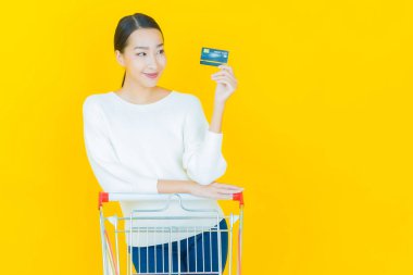 Renkli arka planda süpermarketten alınmış market sepetiyle gülümseyen güzel Asyalı kadın portresi.