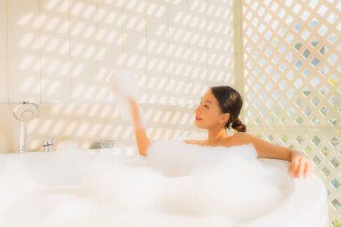 Portre genç Asyalı kadın rahatla spa konsepti için küvette banyo yap.