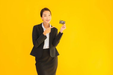 Sarı izole edilmiş arka planda kredi kartı olan güzel, genç Asyalı kadın portresi.