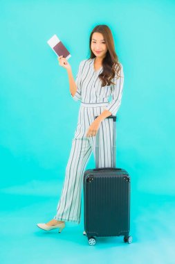 Güzel Asyalı bir kadının portresi. Bavul pasaportu ve biniş kartı mavi arka planda seyahat için hazır.
