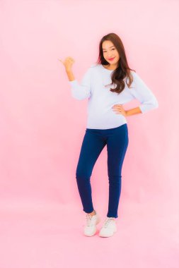 Portrait beautiful young asian woman smile with action on pink isolated background