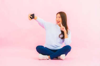 Portrait beautiful young asian woman use smart mobile phone on pink color isolated background