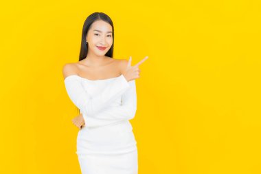 Portre güzel genç iş kadını gülümseyen ve eylem sarı arka planlı Asyalı kadın