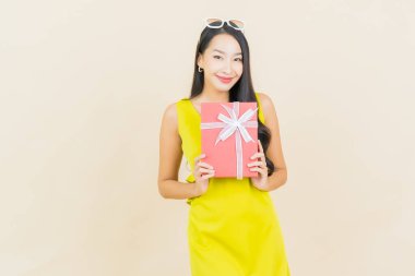 Güzel bir Asyalı kadının portresi. Arka planda kırmızı hediye kutusuyla gülümsüyor.