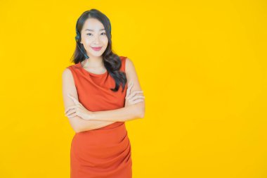 Sarı arka planda çağrı merkezi müşteri hizmetleri merkezi olan güzel Asyalı kadın portresi