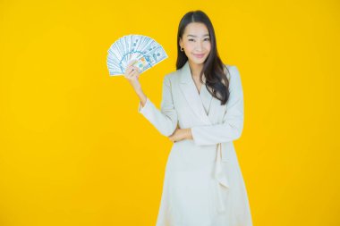 Asyalı güzel bir kadının portresi. Renkli arka planda bol para ve parayla gülümsüyor.