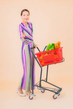 Marketten aldığı alışveriş sepetiyle güzel bir Asyalı kadının portresi. Renkli, izole arka plan.