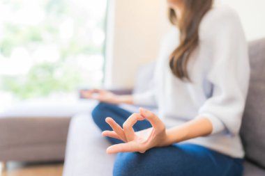 Oturma odasındaki kanepede güzel bir Asyalı kadın meditasyonu.