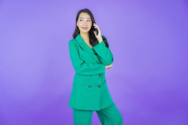 Renkli arka planda akıllı cep telefonuyla güzel Asyalı kadın gülümsemesi