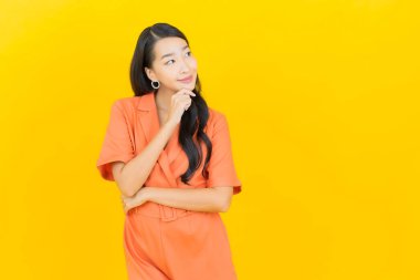 Sarı arka planda poz veren güzel bir Asyalı kadın portresi.