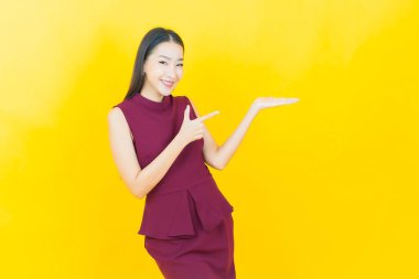 Renkli arka planda bir şey gösteren güzel Asyalı bir kadın portresi.