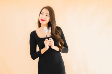 Kaşığı ve çatalı olan güzel Asyalı bir kadının portresi izole edilmiş renkli arka planda yemeye hazır.