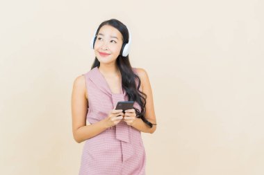 Renkli müzik dinlemek için kulaklığı ve akıllı telefonu olan güzel Asyalı kadın portresi.