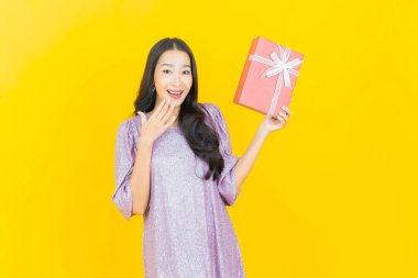 Güzel bir Asyalı kadının portresi. Arka planda kırmızı hediye kutusuyla gülümsüyor.