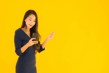 Akıllı cep telefonu, cep telefonu ve kredi kartı sarısı izole bir geçmişi olan güzel Asyalı bir kadın portresi.