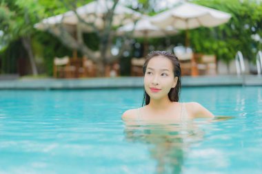 Güzel bir Asyalı kadın portresi. Rahat bir tatil için otel havuzunda yüzme havuzu etrafında gülümse.