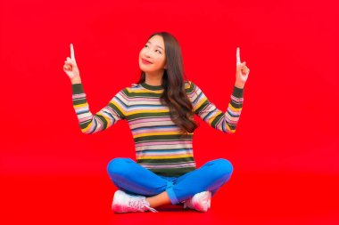 Güzel bir Asyalı kadının portresi. Kırmızı izole edilmiş arka planda hareketli gülümsüyor.