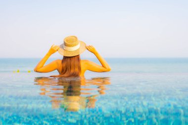 Güzel bir Asyalı kadın portresi. Rahatlayın, gülümseyin. Tatil için oteldeki yüzme havuzunun keyfini çıkarın.