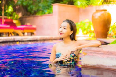 Güzel bir Asyalı kadın portresi. Rahatlayın, gülümseyin. Tatil için oteldeki yüzme havuzunun keyfini çıkarın.