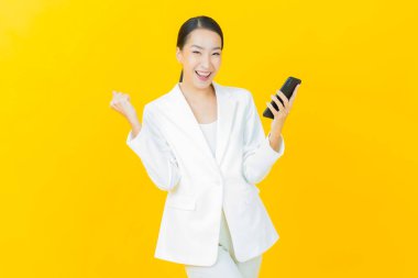 Renkli arka planda akıllı cep telefonuyla güzel Asyalı kadın gülümsemesi