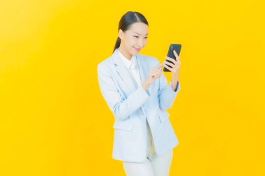 Renkli arka planda akıllı cep telefonuyla güzel Asyalı kadın gülümsemesi