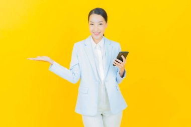 Renkli arka planda akıllı cep telefonuyla güzel Asyalı kadın gülümsemesi