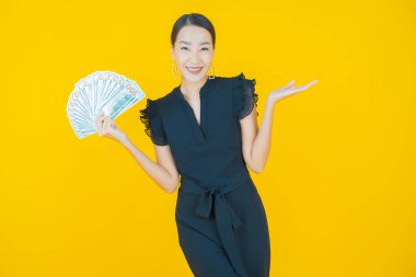 Asyalı güzel bir kadının portresi. Renkli arka planda bol para ve parayla gülümsüyor.