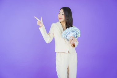 Asyalı güzel bir kadının portresi. Renkli arka planda bol para ve parayla gülümsüyor.