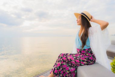 Güzel Asyalı genç kadınların portresi mutlu bir gülümseme deniz kıyısında güneş doğarken ya da batarken rahatla