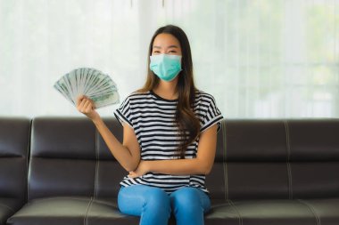 Maskeli güzel Asyalı kadının portresi evde para ya da para gösteriyor.